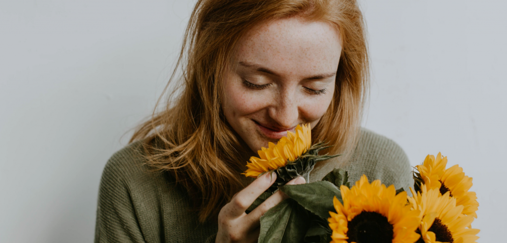 Photo of woman smelling sunflower